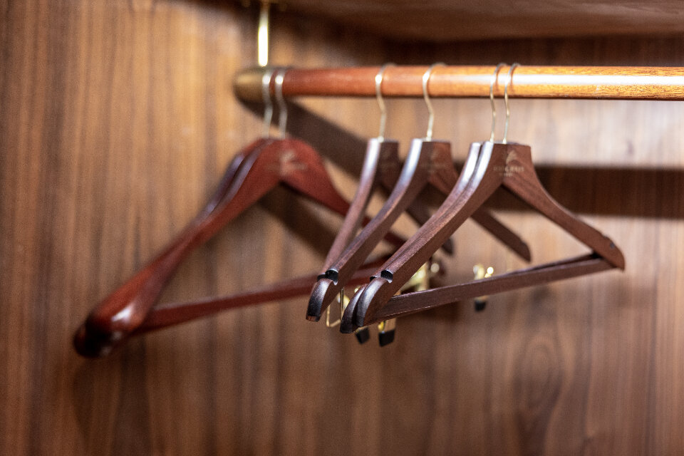 Neatly arranged clothes hanging in a wooden closet
