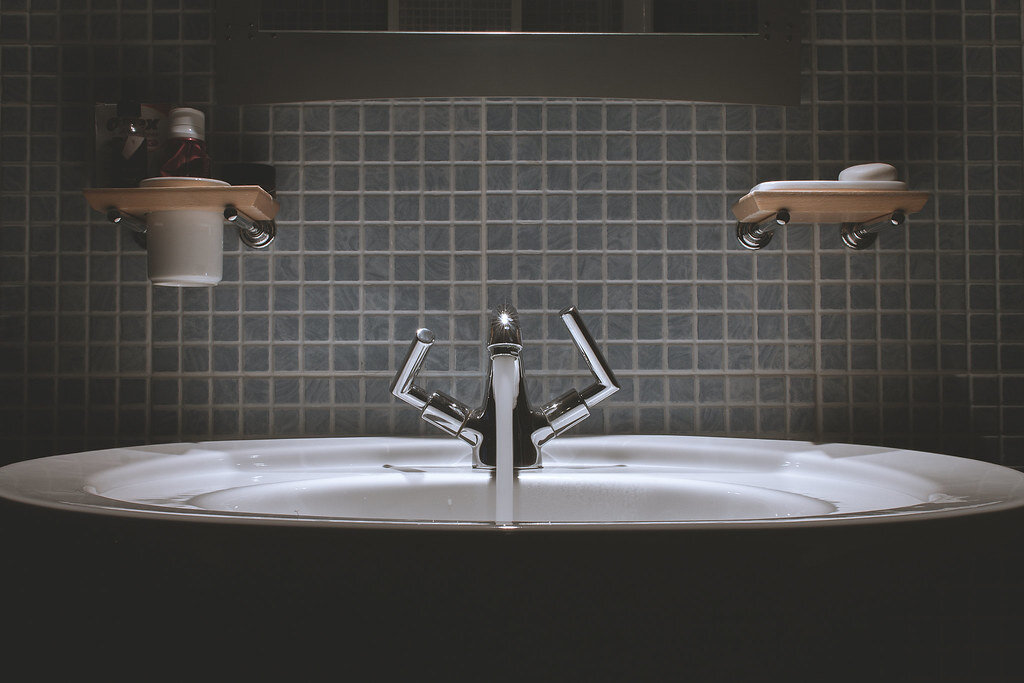 Chrome bathroom faucet with water droplets on a white sink